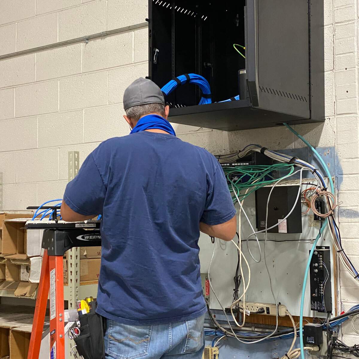 A technician installing a network wall cabinet